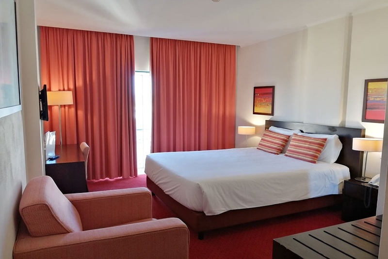Quarto aconchegante no Hotel Monaco com cama de casal, travesseiros decorativos e cortinas elegantes.