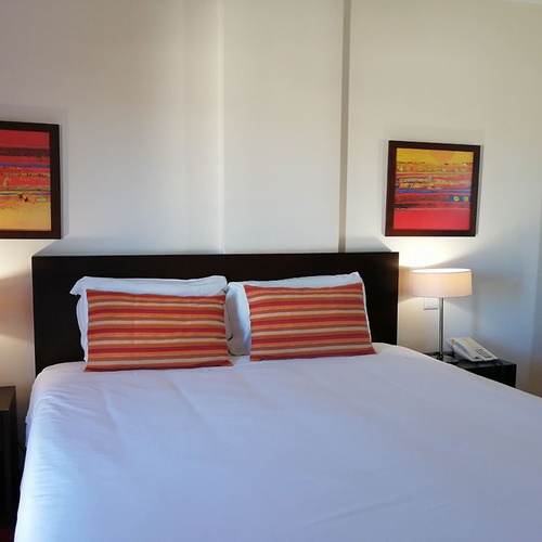Habitación con cama doble, cuadros abstractos y lámpara de noche en Hotel Monaco.