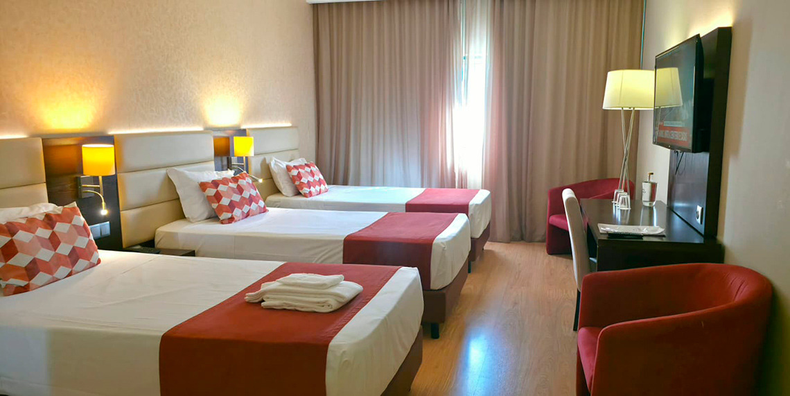 Quarto triplo moderno com camas confortáveis e decoração vibrante. OHotel Monaco oferece um ambiente acolhedor.