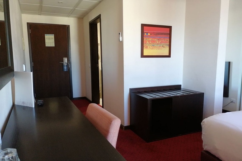 Quarto no Hotel Monaco com cama, poltronas e espelho grande.