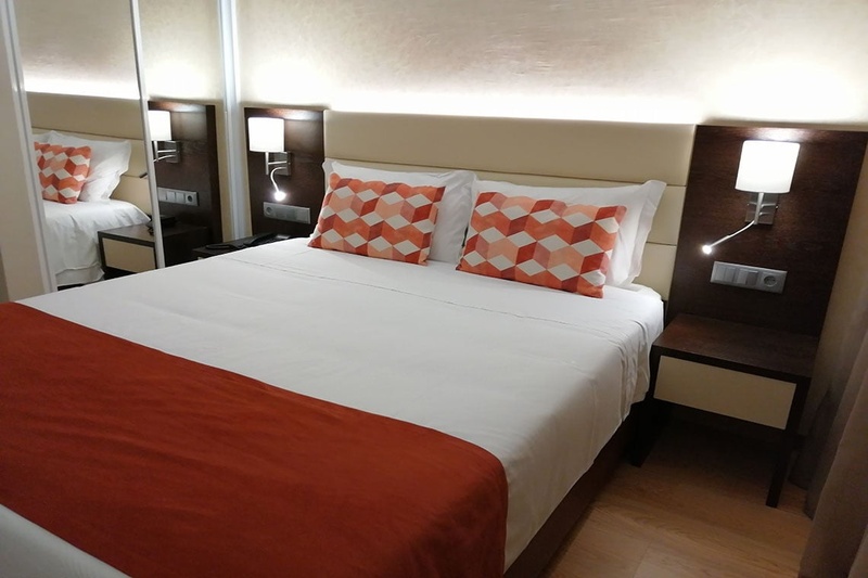 Quarto aconchegante no Hotel Monaco com cama de casal, travesseiros decorativos e cortinas elegantes.