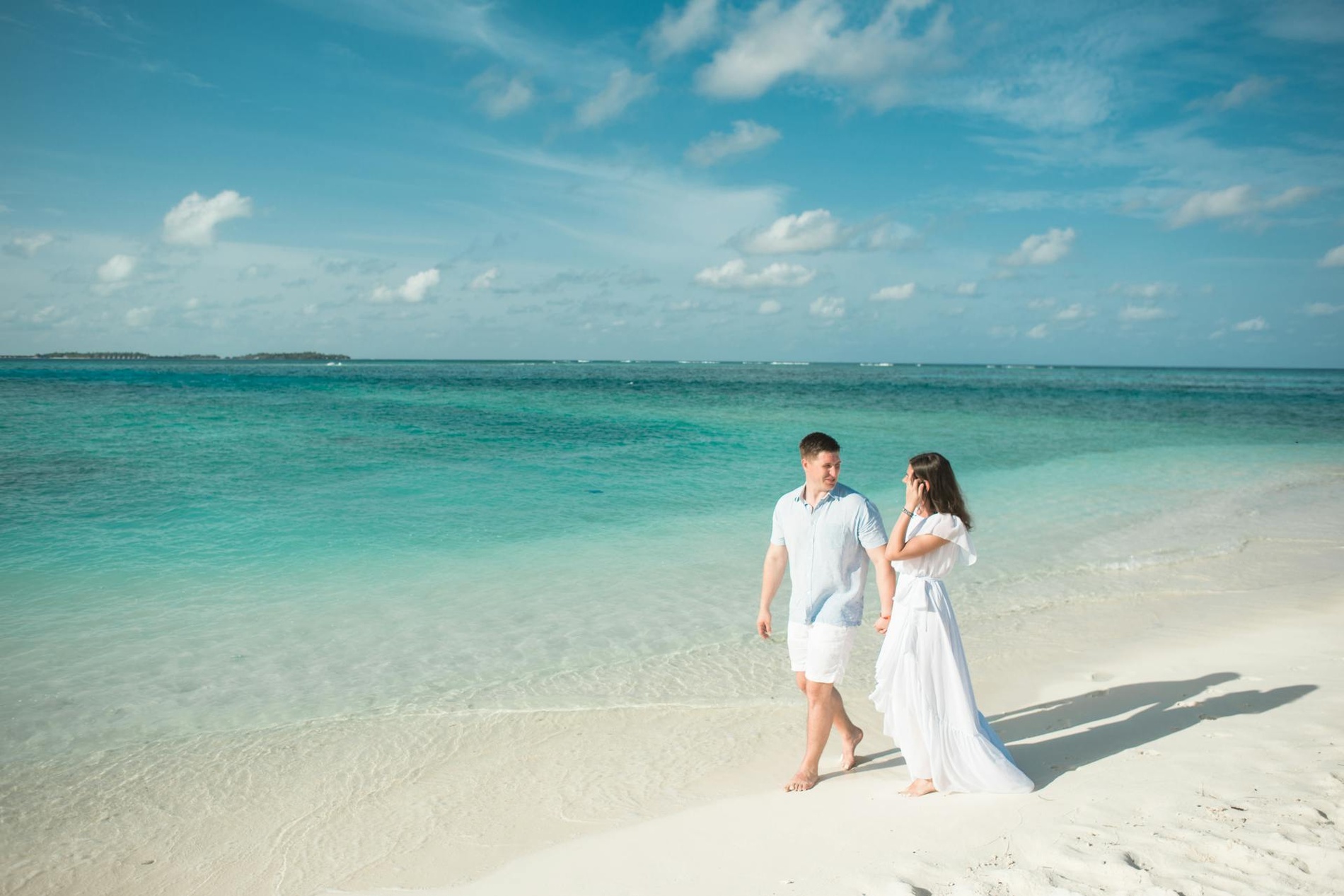 Casal em praia paradisíaca, com águas cristalinas e areia branca. Perfeito para férias românticas no Hotel Monaco.