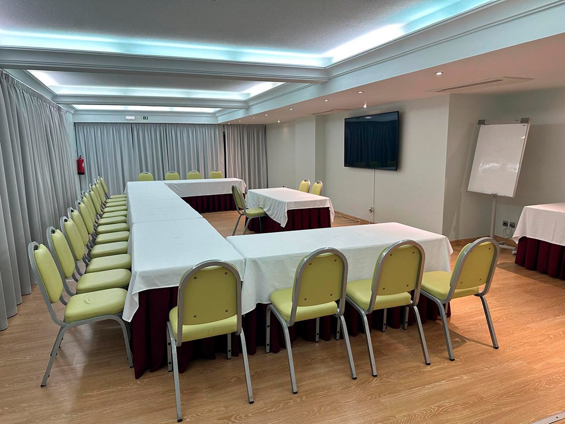 Salão de eventos com mesas em U, cadeiras amarelas e flip chart. Ideal para Hotel Monaco.