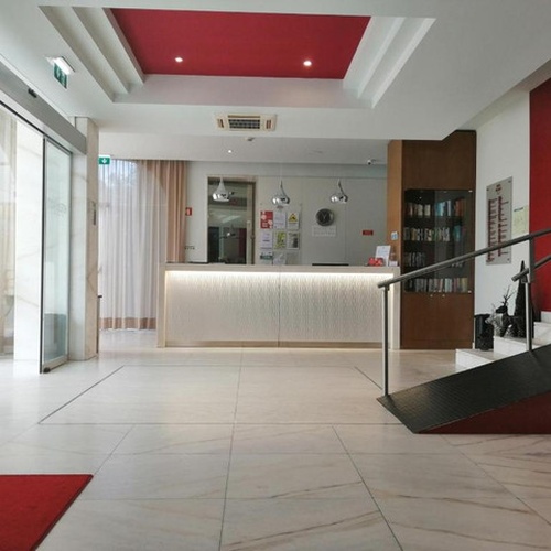 Recepción luminosa y moderna del Hotel Monaco con escaleras y mostrador de bienvenida.