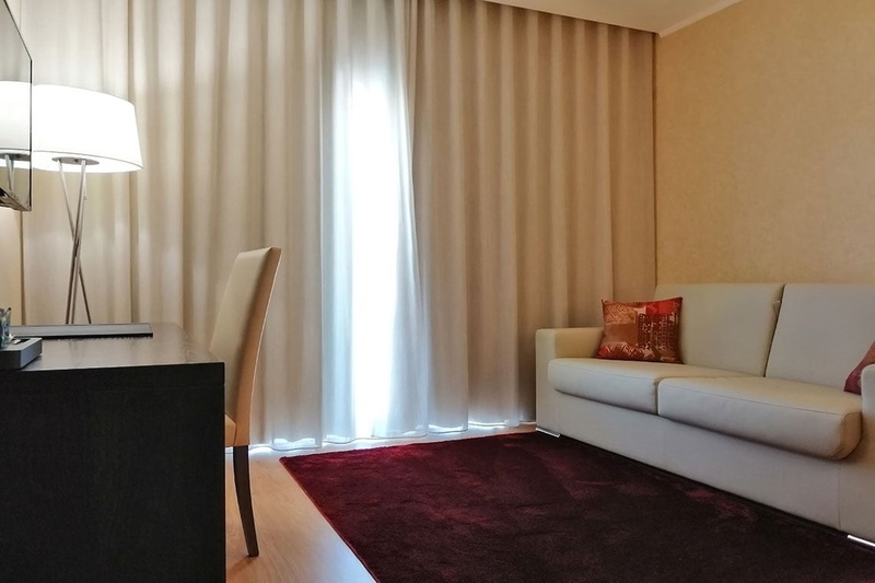 Quarto de hotel confortável no Hotel Monaco com cama branca, colcha vermelha e almofadas decorativas.