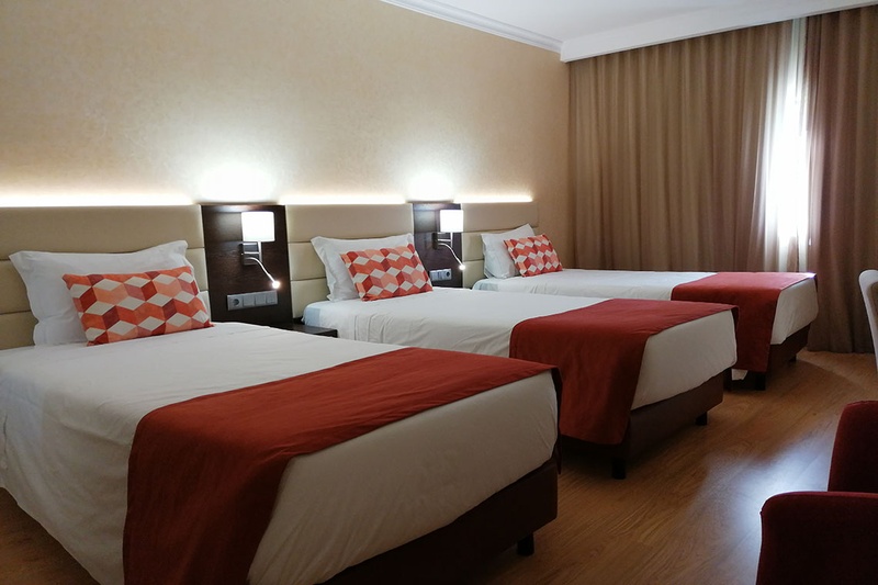Quarto triplo no Hotel Monaco com três camas, decoração moderna e aconchegante.