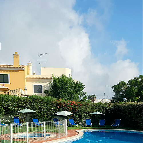 Piscina exterior azul com espreguiçadeiras e guarda-sóis num hotel com Hotel Monaco.