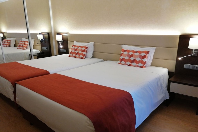 Quartos duplos no Hotel Monaco com roupa de cama branca e mantas laranja.