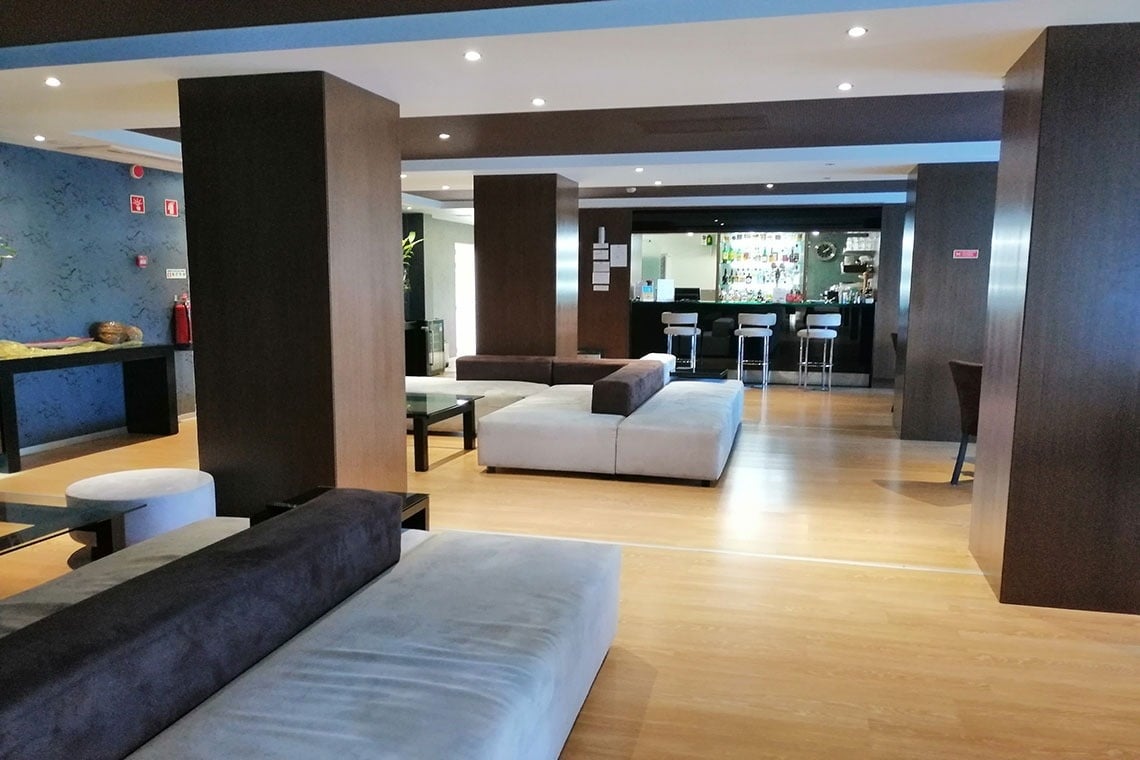 Lobby moderno do Hotel Monaco com bar e sofás aconchegantes.