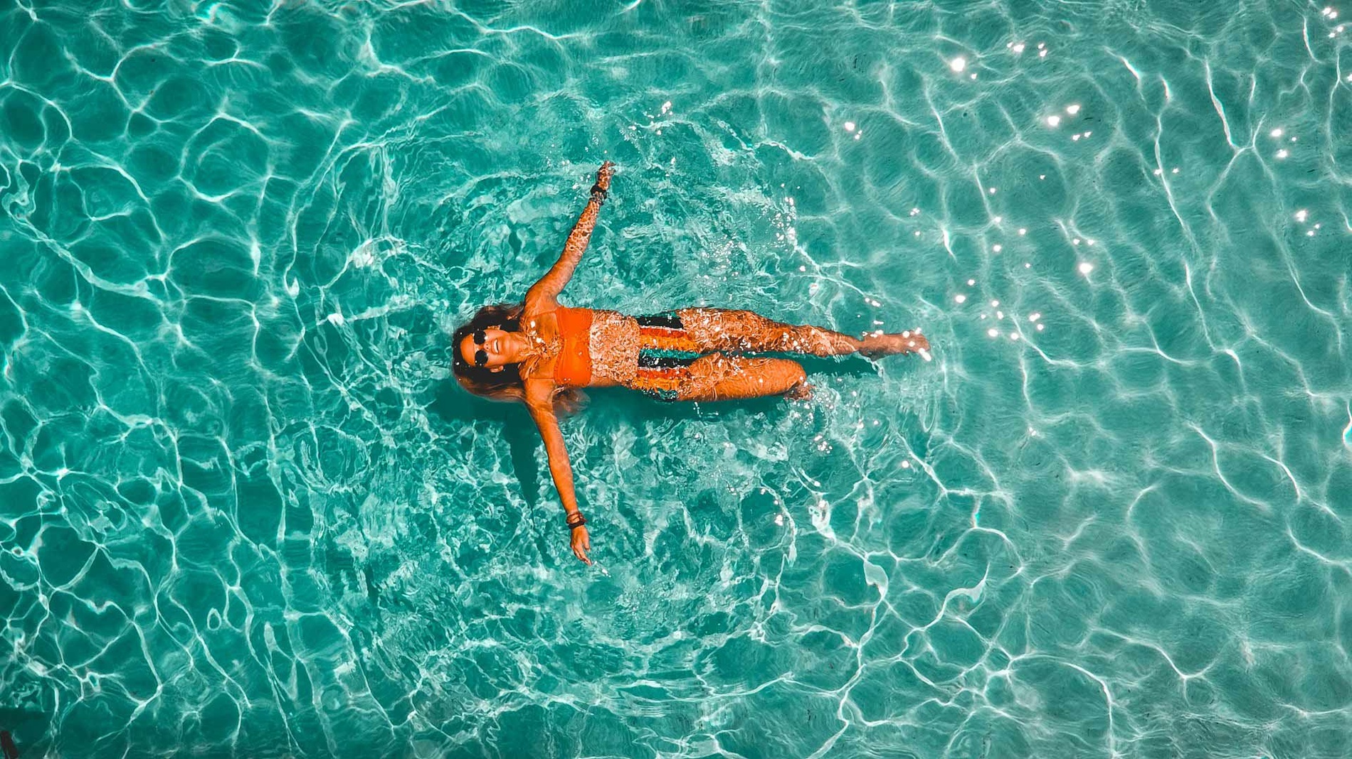 Mulher flutua relaxada na piscina cristalina do Hotel Monaco.