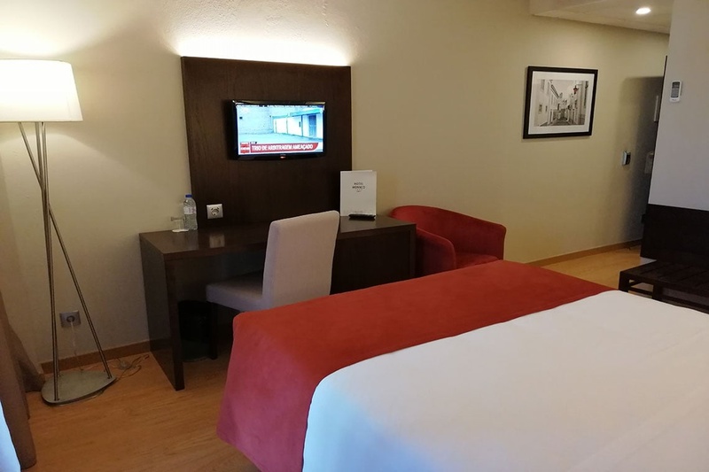 Quarto no Hotel Monaco com cama, poltronas e espelho grande.