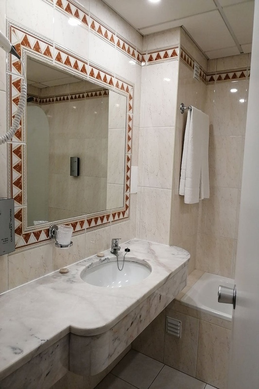 Quartos duplos no Hotel Monaco com roupa de cama branca e mantas laranja.