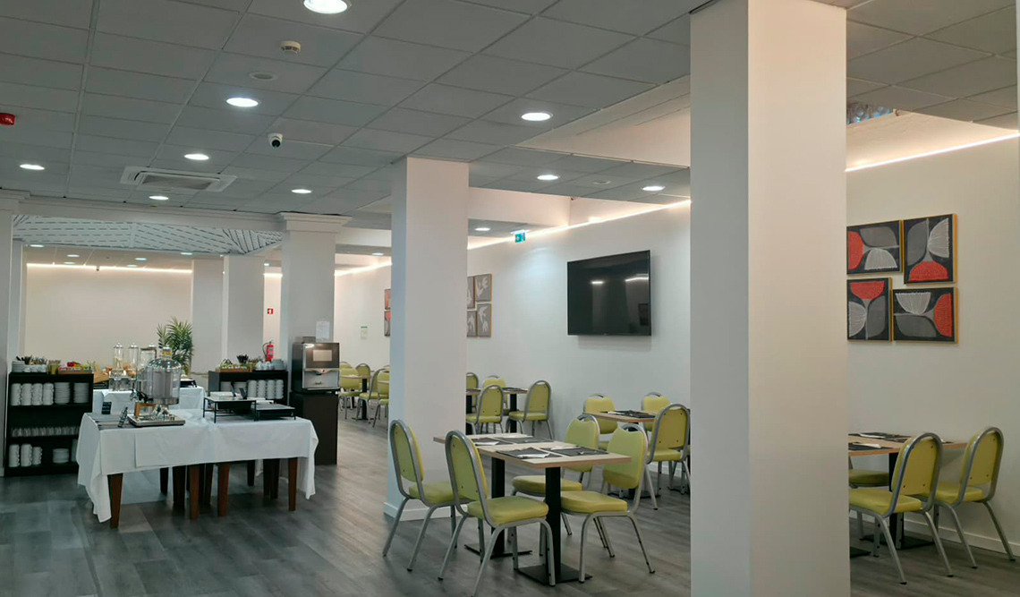 Salão do Hotel Mónaco com mesas postas e buffet pronto.