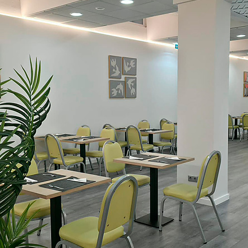 Sala de jantar de hotel com mesas e cadeiras amarelas, pronta para receberHotel Monaco.
