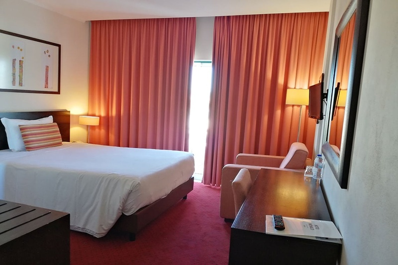 Quarto no Hotel Monaco com cama, poltronas e espelho grande.