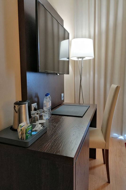 Quarto de hotel confortável no Hotel Monaco com cama branca, colcha vermelha e almofadas decorativas.
