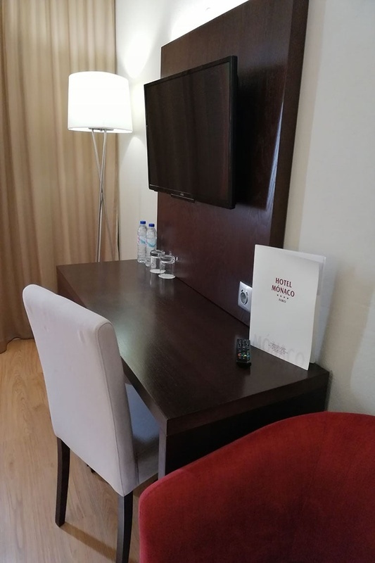 Quarto aconchegante no Hotel Monaco com cama de casal, travesseiros decorativos e cortinas elegantes.