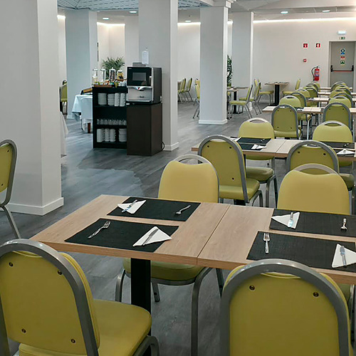 Salão de buffet de hotel com mesas e cadeiras amarelas, pronto para o Hotel Monaco.