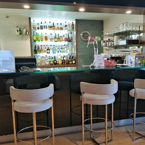 Bar moderno del Hotel Monaco con taburetes y bebidas.
