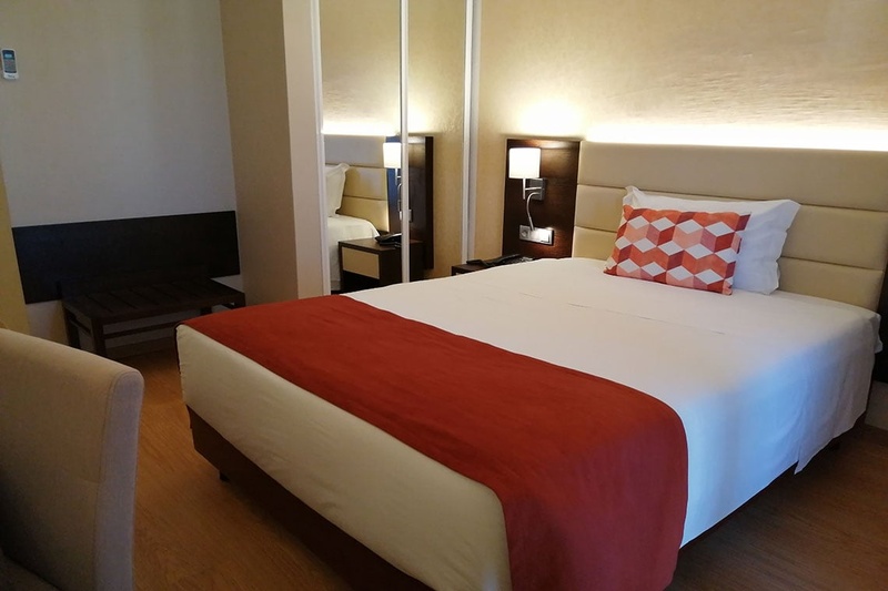Quarto no Hotel Monaco com cama, poltronas e espelho grande.