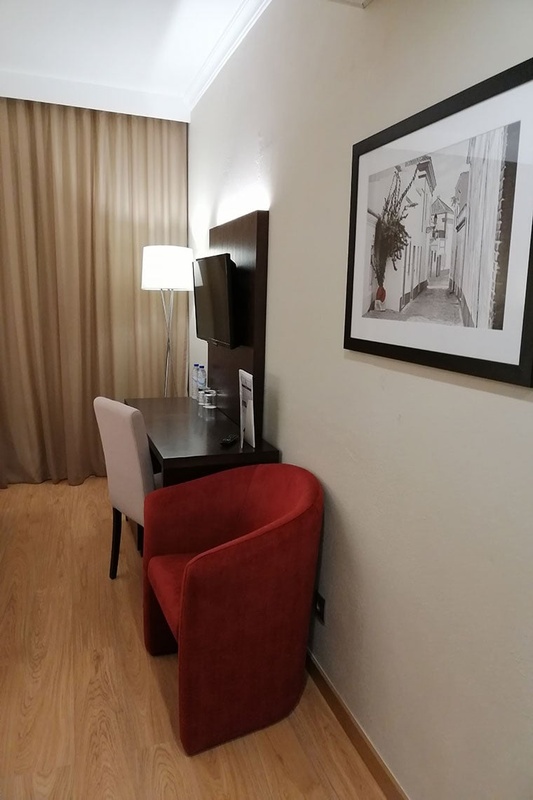 Quarto aconchegante no Hotel Monaco com cama de casal, travesseiros decorativos e cortinas elegantes.