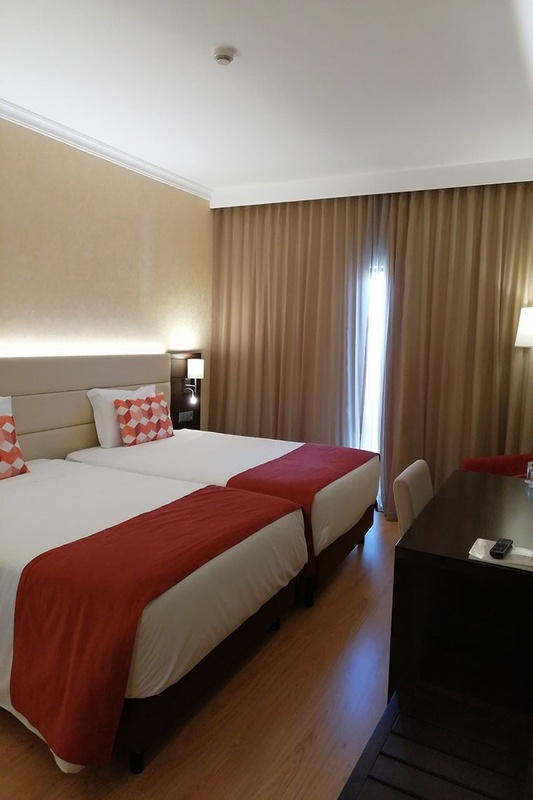 Quartos duplos no Hotel Monaco com roupa de cama branca e mantas laranja.