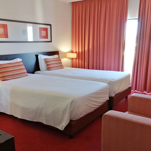 Habitación twin en Hotel Monaco con decoración moderna y cortinas rosas.