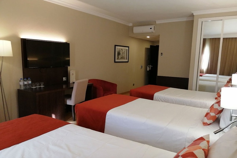Quarto triplo no Hotel Monaco com três camas, decoração moderna e aconchegante.