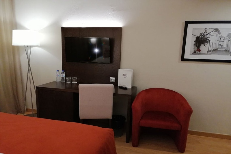 Quarto aconchegante no Hotel Monaco com cama de casal, travesseiros decorativos e cortinas elegantes.