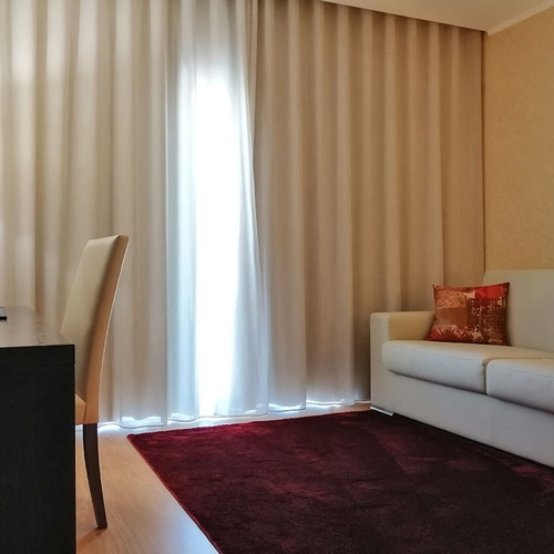 Cómoda habitación en Hotel Monaco con sofá, escritorio y cortinas luminosas.