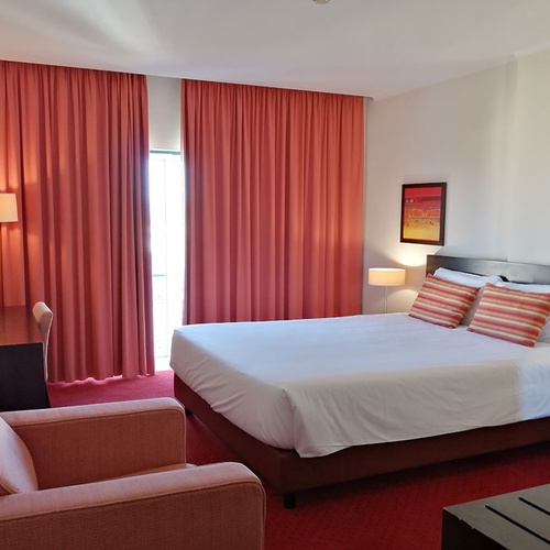 Habitación espaciosa y luminosa en Hotel Monaco con cama cómoda y sillón.