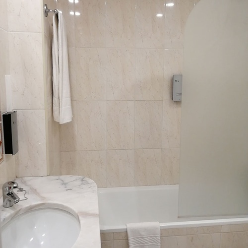 Baño moderno en Hotel Monaco con ducha, lavabo y toalla blanca.