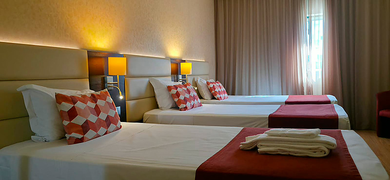 Quarto triplo no Hotel Monaco com três camas, decoração moderna e aconchegante.