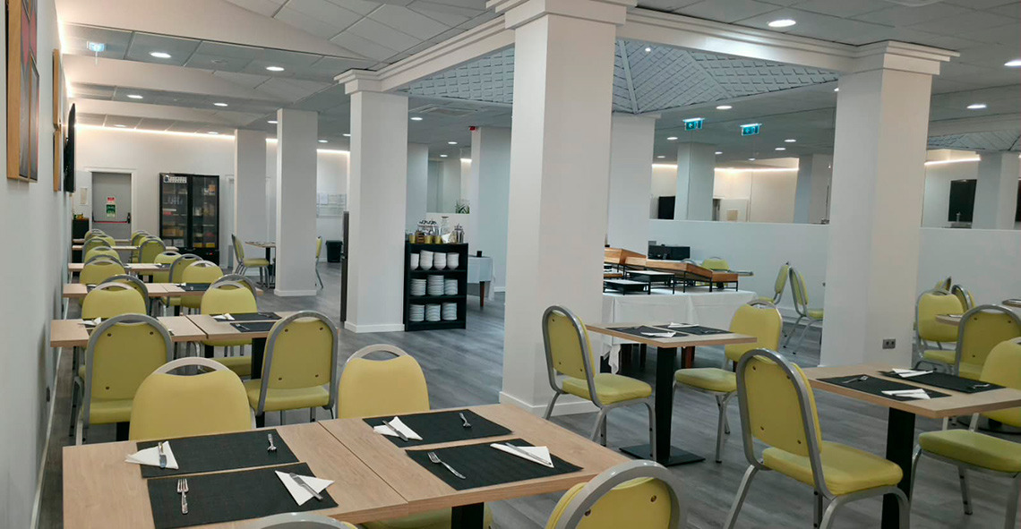 Sala de jantar do Hotel Monaco com mesas postas e cadeiras de madeira.