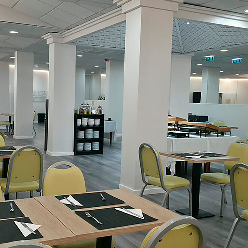 Salão de café da manhã do hotel com mesas e cadeiras amarelas, pronto para Hotel Monaco.