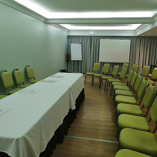 Sala de conferências do hotel com mesas e cadeiras verdes, pronta para um evento. Hotel Monaco