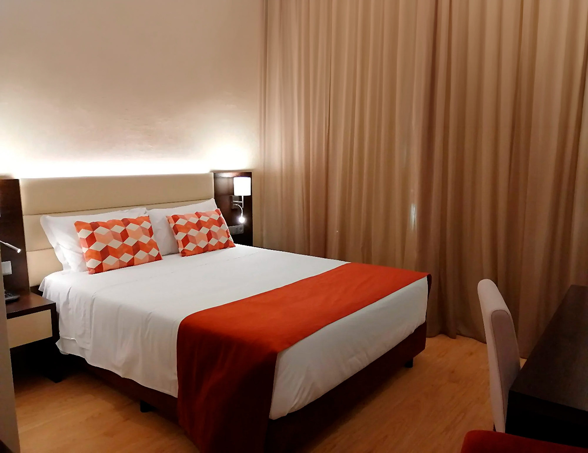 Quarto elegante com cama de casal, travesseiros decorados e piso de madeira no Hotel Monaco.