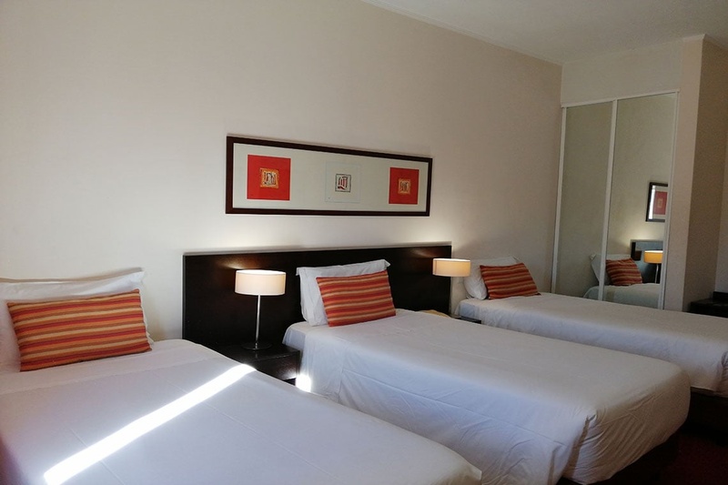 Quarto triplo no Hotel Monaco com três camas, decoração moderna e aconchegante.