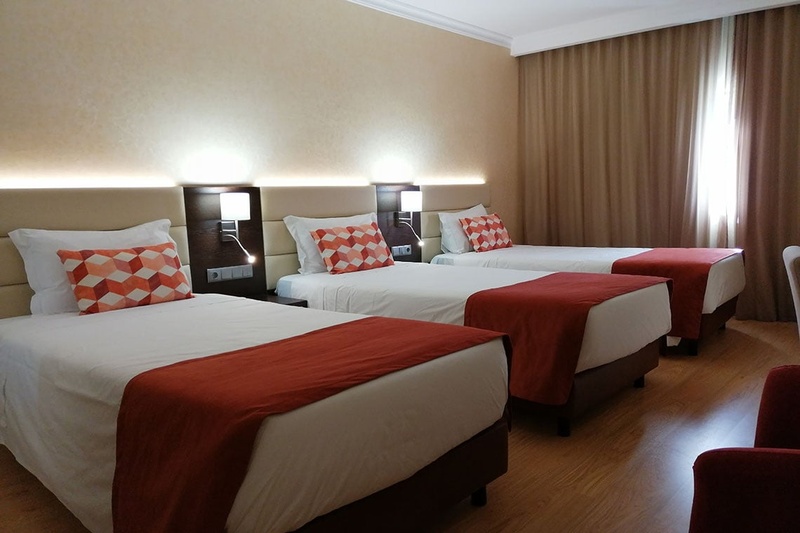 Quarto triplo no Hotel Monaco com três camas, decoração moderna e aconchegante.