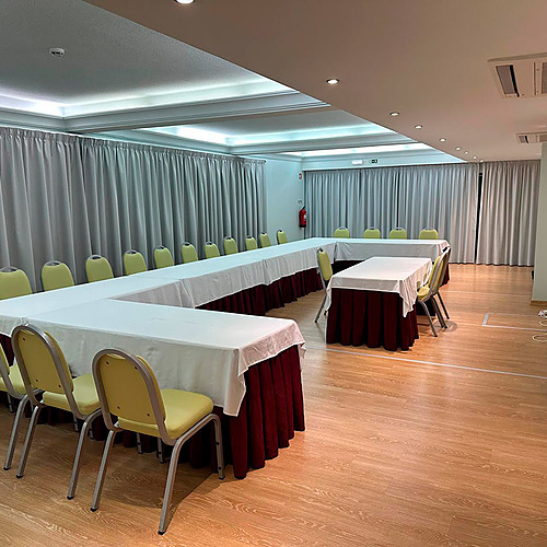 Sala de conferências com mesas em U e cadeiras amarelas, ideal para Hotel Monaco.