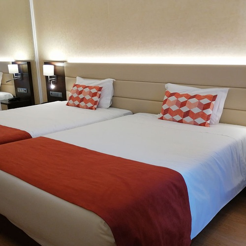 Habitación con dos camas individuales y mantas naranjas en Hotel Monaco.