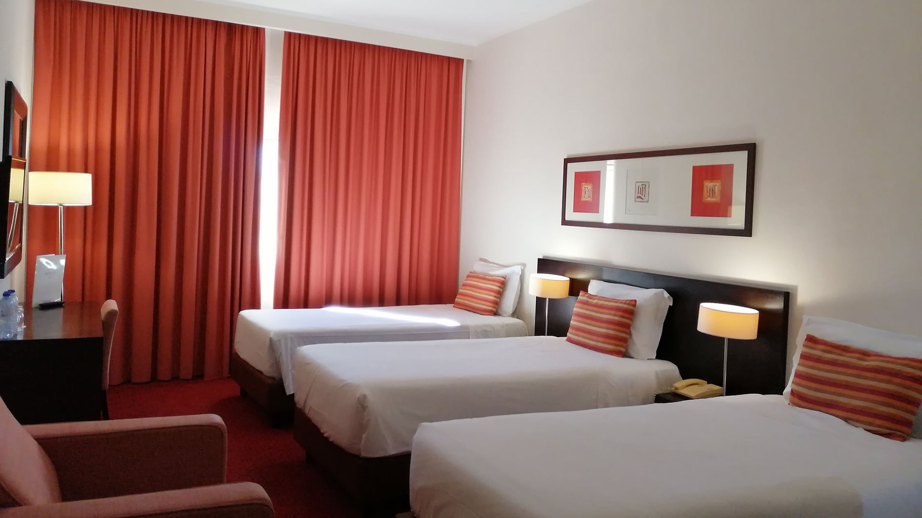 Hotel Monaco: Quarto triplo com três camas de solteiro, cortinas laranjas e arte.