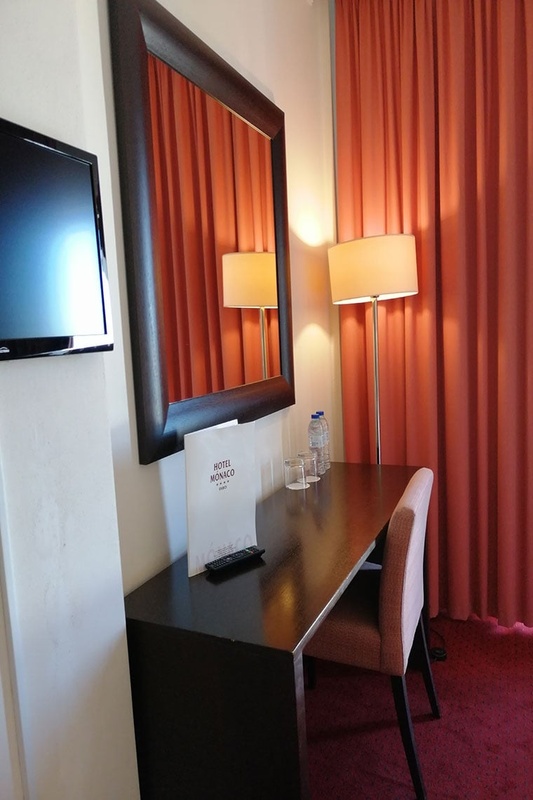 Quarto aconchegante no Hotel Monaco com cama de casal, travesseiros decorativos e cortinas elegantes.