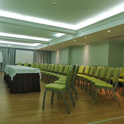Sala de conferências moderna com cadeiras verdes e mesa em Hotel Monaco.