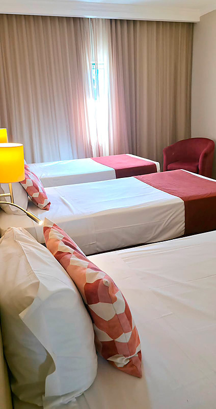 Quarto triplo no Hotel Monaco com três camas, decoração moderna e aconchegante.