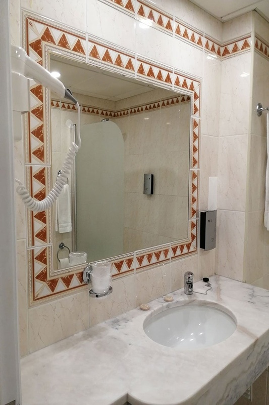 Quarto aconchegante no Hotel Monaco com cama de casal, travesseiros decorativos e cortinas elegantes.
