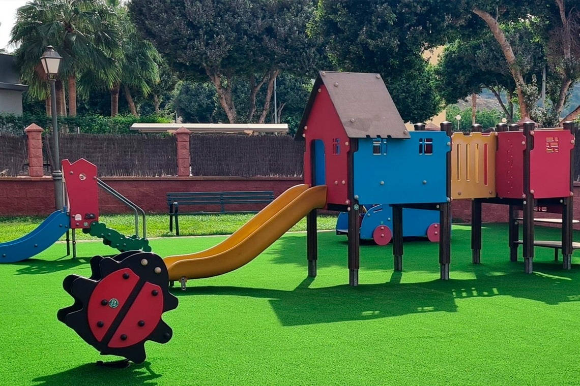 une aire de jeux colorée avec un toboggan et une coccinelle