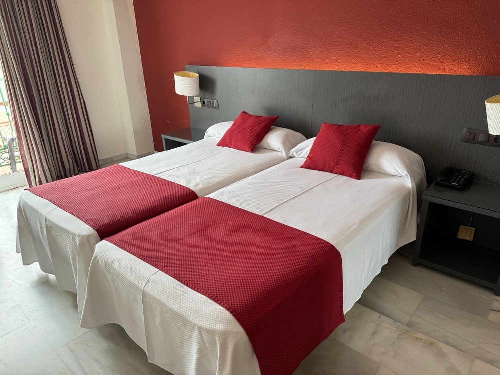 two beds in a hotel room with red pillows