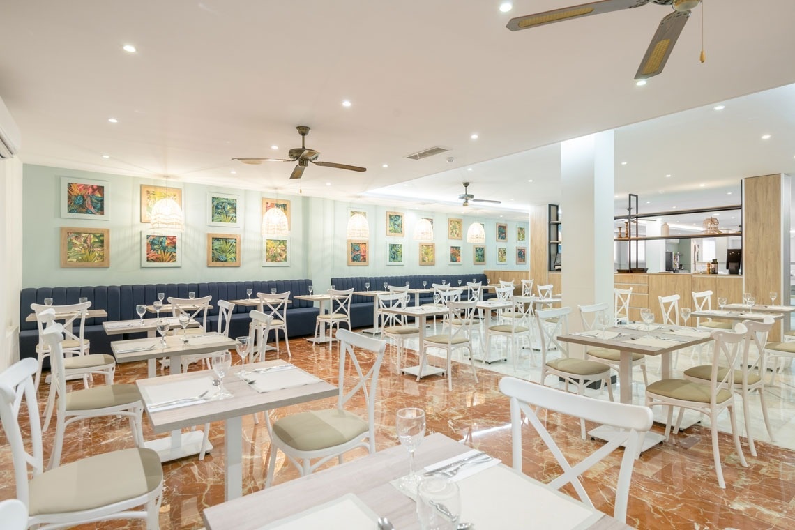 un restaurante lleno de mesas y sillas con ventiladores de techo