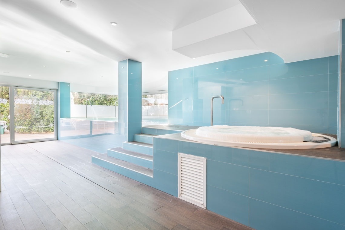 un jacuzzi en un baño con azulejos azules y escaleras